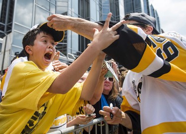Pittsburgh Penguins Marc-Andre Fleury places a hat on the head of a young fan during the team's Stanley Cup NHL hockey victory parade on Wednesday, June 14, 2017, in Pittsburgh.(Steph Chambers/Pittsburgh Post-Gazette via AP)