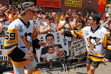 Pittsburgh Penguins' Jake Guentzel (59) and Conor Sheary, right, celebrate with fans along the Stanley Cup victory parade route in Pittsburgh, Wednesday, June 14, 2017. (AP Photo/Gene J. Puskar)