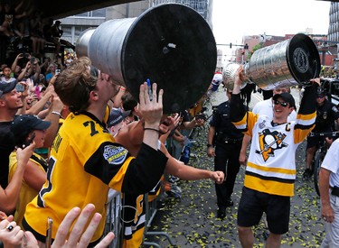 Pittsburgh Penguins' Sidney Crosby, right, hoists the Stanley Cup as he passes a fan kissing his replica along the Stanley Cup victory parade route in Pittsburgh, Wednesday, June 14, 2017. (AP Photo/Gene J. Puskar)