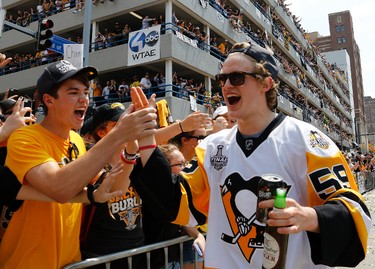 Pittsburgh Penguins' Jake Guentzel (59) celebrates with fans as he walks along the route during the team's Stanley Cup NHL hockey victory parade on Wednesday, June 14, 2017, in Pittsburgh. (AP Photo/Gene J. Puskar)
