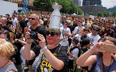 Pittsburgh Penguins fans including Christine Szymarek, of White Oak, Penn., wears a replica of the Stanley Cup hat, in the crowd at Point State Park during the team's Stanley Cup NHL hockey victory parade on Wednesday, June 14, 2017, in Pittsburgh. (AP Photo/Gene J. Puskar)