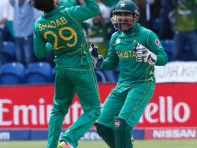 Pakistan captain Sarfraz Ahmed (right) and teammate Shadab Khan celebrate taking the wicket of England’s Joe Root during the ICC Champions Trophy semifinal on June 14, 2017. (KIRSTY WIGGLESWORTH/AP)