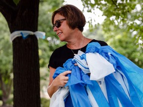 Alison Lebrun helps tie blue-and-white awareness ribbons along Springfield Pike near the family home of Otto Warmbier, who was imprisoned in North Korea in March 2016, in the Wyoming suburb of Cincinnati on Tuesday, June 13, 2017. (AP Photo/John Minchillo)