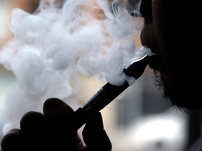 In this April 23, 2014 file photo, a man smokes an electronic cigarette in Chicago. A large government survey released Thursday, June 15, 2017, suggests the number of U.S. high school and middle school students using electronic cigarettes fell to 2.2 million last year, from 3 million the year before. (AP Photo/Nam Y. Huh, File)