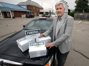 Funeral director Joe O'Neil just received shipment of new funeral procession car signs which may not be used now that the city's new red light cameras would penalized mourners driving through intersections during funerals. (MORRIS LAMONT, The London Free Press)