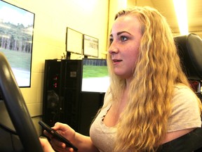 Katie Johnston, 14, tries to watch the road on a video screen while responding to a text as part of a simulation at Northern Collegiate Thursday. The school recently was gifted a state-of-the-art driving simulator it's using to teach students about distracted driving. Tyler Kula/Sarnia Observer/Postmedia Network