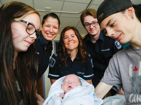 Luke Hendry/The Intelligencer 
New parents Angel Thibault and Troy Brant of Belleville hold their son, Troy Junior Brant, Thursday at Belleville General Hospital. He was born three months premature April 8. Tending his mother during the delivery were Hastings-Quinte paramedics Autumn Belnap, background left, Danielle Spitzig and Logan French, who at the time was a student.