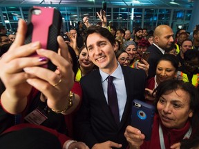 Canadian Prime Minister Justin Trudeau poses for selfies with workers before he greets refugees from Syria at Pearson International airport, in Toronto, on Thursday, Dec. 10, 2015. (THE CANADIAN PRESS/Nathan Denette)