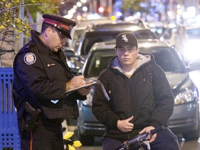 Toronto Police Officer Frank Girmenia of Traffic Services hands out a ticket for not having a light. - Light Up 54 Division. Bike Blitz takes place along Danforth Avenue after 3 weeks of education that saw 450 pamphlets passed out to cyclists and also numerous cautions we given to first time offenders ahead of tonight's blitz. (GREG HENKANHAF/TORONTO SUN FILES)