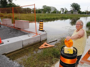 Luke Hendry/The Intelligencer
Jackie Thompson stands amid the barriers to flooding near her South John Street home Saturday. She expressed no complaints about the city's response to flooding, but some residents criticize what they said was delayed action.