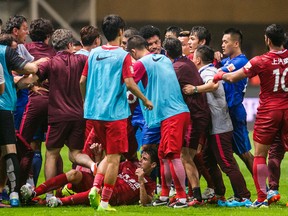 In this Sunday, June 18, 2017 photo, Shanghai SIPG players, red jersey, and Guangzhou R&F players, blue jersey, tussle during their Chinese Super League match in Guangzhou. (Color China Photo via AP)