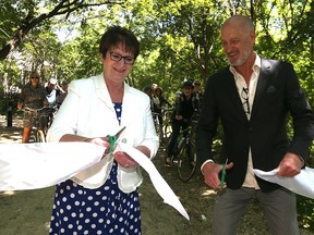 Eileen Clarke (left), Minister of Indigenous and Municipal Relations, and Paul Jordan, CEO of The Forks North Portage, cut the ribbon following an announcement about the South Point Douglas Trail project on the riverbank at Annabella Street near Higgins Avenue in Winnipeg on Mon., June 19, 2017. Kevin King/Winnipeg Sun/Postmedia Network