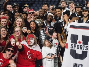 Members of the Carleton Ravens men’s basketball team pose with fans while holding the trophy after winning USports basketball national championship. (THE CANADIAN PRESS)