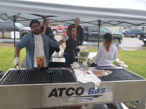 Tarun Malik (left), a community disability services practitioner, helps work the barbecue at the ECHO Society fundraiser (Jeremy Appel | Whitecourt Star).