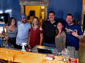 Brewery founders Adam and Brittney Wilgosh (middle) and Dan Christensen (left) with employees celebrated behind the bar in the tap room of the Oldman River Brewery, Ltd., during their wildly successful sneak peek event.