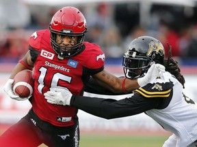 Calgary Stampeders slotback Marquay McDaniel tries to run away from the clutches of Hamilton Tiger-Cats linebacker Rico Murray in Calgary on Sunday, Aug. 28, 2016. (THE CANADIAN PRESS/Larry MacDougal)