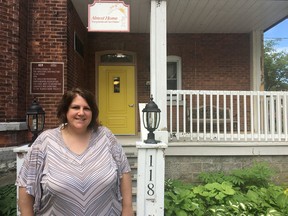 Laurie Morgan, executive director of Almost Home, poses in front of Almost Home's signature yellow door at 118 William St.. (Ashley Rhamey/The Whig-Standard)