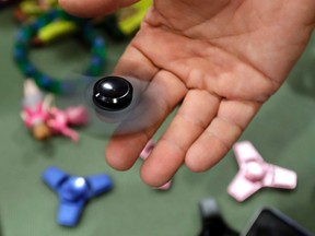 In this May 11, 2017, file photo, Funky Monkey Toys store owner Tom Jones plays with a fidget spinner in Oxford, Mich. Fidget spinners are among the those on the annual list of hazardous summer toys compiled by World Against Toys Causing Harm, Inc., a nonprofit consumer watchdog. (AP Photo/Carlos Osorio, File)
