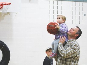 Dad Daniel Hartley helps his youngest daughter, Helen, shoot a basket at St. Anthony School's annual Doughnuts for Dads event held in the school gymnasium.