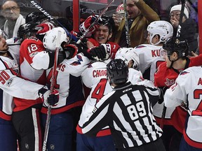 Washington Capitals players swarm Ottawa Senators right winger Curtis Lazar (27), back, during NHL action in Ottawa on Tuesday, Jan. 24, 2017. (THE CANADIAN PRESS/Sean Kilpatrick)