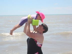 Jaci Oliver holds up Alexandra, 2, at the Port Stanley main beach on Wednesday afternoon. Lake Erie’s average water level for May was at an all time high. (Laura Broadley/Times-Journal)