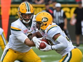 Edmonton Eskimos quarterback Mike Reilly hands the ball to running back John White against the Calgary Stampeders during a preseason CFL game at Commonwealth Stadium in Edmonton, June 11, 2017.