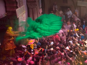 A Hindu priest throws coloured powder on devotees inside Banke Bihari temple during Holi festival celebrations in Vrindavan, India, on March 10, 2017. India's population is expected to surpass China by the year 2050. (AP Photo/Manish Swarup)