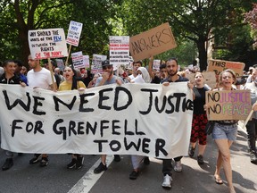 Demonstrators hold a banner demanding justice for the victims of the recent deadly apartment block fire at Grenfell Tower, as they march towards parliament in central London Wednesday June 21, 2017. The mass "Day of Rage" demonstration is timed to coincide with the state opening of parliament Wednesday. (AP Photo / Matt Dunham)
