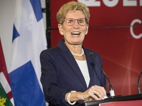 Ontario Premier Kathleen Wynne speaks from a podium before signing an agreement with Quebec Premier Philippe Couillard following a joint meeting of cabinet ministers in Toronto on Friday, October 21, 2016. THE CANADIAN PRESS/Chris Young