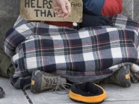 A panhandler receives some coin on the streets of Toronto. (Veronica Henri/Toronto Sun files)