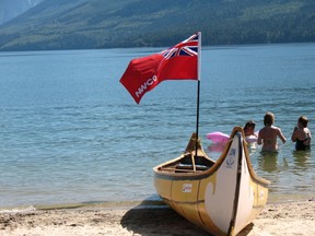 A canoe rests on a beach as children play in the water (Submitted photo | Ted Bentley).