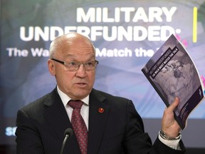 Standing Senate Committee on National Security and Defence Chair Senator Daniel Lang holds up a copy of the Defence Policy Report during a news conference in Ottawa on April 13, 2017. Lang announced his resignation on Thursday, June 22. (THE CANADIAN PRESS/Adrian Wyld)