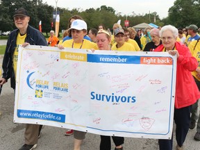 BRUCE BELL/the intelligencer
Dr. Douglas MacIntosh (left) his wife Catherine (far right) get a hand from cancer survivors Donna Nixon (second from left) and Candace O'Hara with the Relay for Life banner during the Survivor Lap Friday night at Loyalist College.