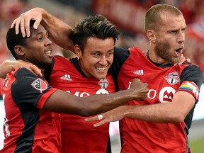 TFC’s Armando Cooper (left) celebrates after assisting on the Reds’ opening goal last night. (THE CANADIAN PRESS)