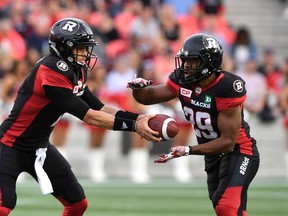 Redblacks quarterback Trevor Harris hands the ball off to William Powell during last night’s game. (THE CANADIAN PRESS)
