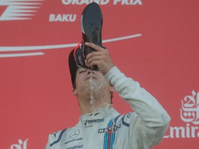 Williams driver Lance Stroll of Canada, third placed, takes a celebratory drink from the boot of Red Bull driver Daniel Ricciardo of Australia, who won the Formula One Azerbaijan Grand Prix in Baku, Azerbaijan, Sunday, June 25, 2017. Stroll placed third for his first ever podium finish. (AP Photo/Efrem Lukatsky)