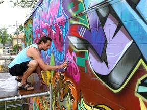 Josh, a graffiti artist who goes by the handle Fatso, finishes off his section of a mural wall painted by about 20 graffiti artists in a weekend event outside the Life of Leisure Surf and Social Club store  at 792 Dundas St. in London?s Old East Village.  (Mike Hensen/The London Free Press)