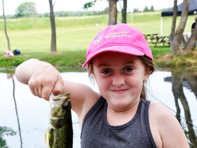 Natasha Merrill, 8, of Staffa, tried to contain her smile as she holds this fish she caught at the Mitchell Fish & Game Club outside Fullarton June 17. ANDY BADER/MITCHELL ADVOCATE