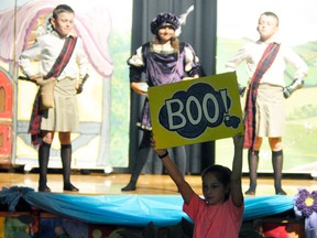Morgan Millar (foreground) holds a BOO! Sign when Baron Smug (center, played by Stephanie Phillips) and her henchmen, Kale Murray (left) and Luke Murray appear on stage. ANDY BADER/MITCHELL ADVOCATE