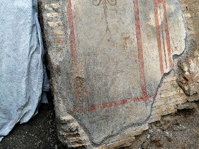 This photo made available Monday, June 26, 2017, by the Italian Culture Ministry, shows a frescoed wall segment, part of the charred ruins of a 3rd-century building that was unearthed while digging for Rome's new subway.(Italian Culture Ministry Via AP)