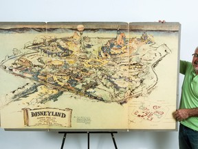 In this April 28, 2017, file photo art dealer Mike Van Eaton stands next to a hand-drawn map from 1953 that shows Walt Disney's original ideas for Disneyland displayed at the Van Eaton Galleries in Sherman Oaks area of Los Angeles. The hand-drawn map that shows Walt Disney’s original ideas for Disneyland has sold at auction for $708,000. (AP Photo/Damian Dovarganes, File)
