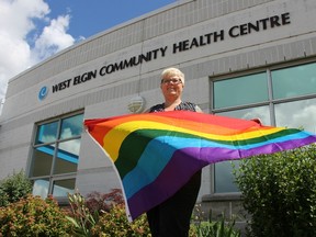 Becky Thomson, who identifies herself as a member of the LGBTQ community, holds a pride flag in front of the West Elgin Community Health Centre in West Lorne. She’s organizing the first ever pride flag raising event in West Elgin, which is taking place July 12. (JONATHAN JUHA/ TIMES-JOURNAL/ POSTMEDIA NETWORK)