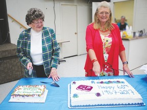 (l. to r.) Olga  Brown, representing the Women’s Institute, and Lyndara Cowper-Smith cut anniversary cakes celebrating 60 years of service to the community. (See story on  Page  4)