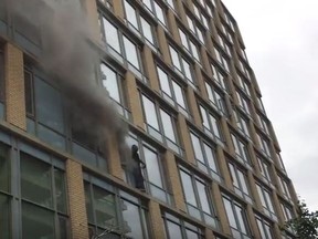 Smoke billows out behind a man standing on the ledge of a Sherbourne St. building on Tuesday, June 27, 2017. (YouTube screengrab)