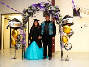 During the Grand March announcing Piikani Nation Secondary School's 2017's graduands, Tori Potts, class valedictorian, stops underneath the floral arch with her escort for photos.