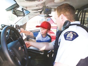Sgt. Troy Dobson holds the thermal imaging camera for Trishelle Bruneau during a tour Vulcan Prairieview Elementary School students took of the Vulcan RCMP detachment June 20. Jasmine O’Halloran Vulcan Advocate