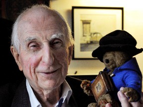 In this June 12, 2015 file photo, Michael Bond poses with a soft toy version of Paddington bear. Publisher HarperCollins says Michael Bond, creator of globe-trotting teddy Paddington bear, died on Tuesday June 27, 2017, aged 91. (Nick Ansell/PA via AP)