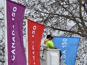 Workers put up Canada 150 flags on poles just outside the entrance to Hawrelak Park in Edmonton on April 18, 2017. (Ed Kaiser/Postmedia Network)