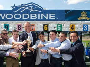 Woodbine chief executive officer Jim Lawson (centre)  holds the Queen’s Plate trophy after the post position draw on Wednesday. (Michael Burns/photo)