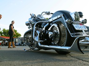 Riders walk past a Harley Davidson Heritage Softail Classic motorcycle at Peterborough Cycle Salvage on Thursday July 9, 2015. (Clifford Skarstedt/Postmedia Network)